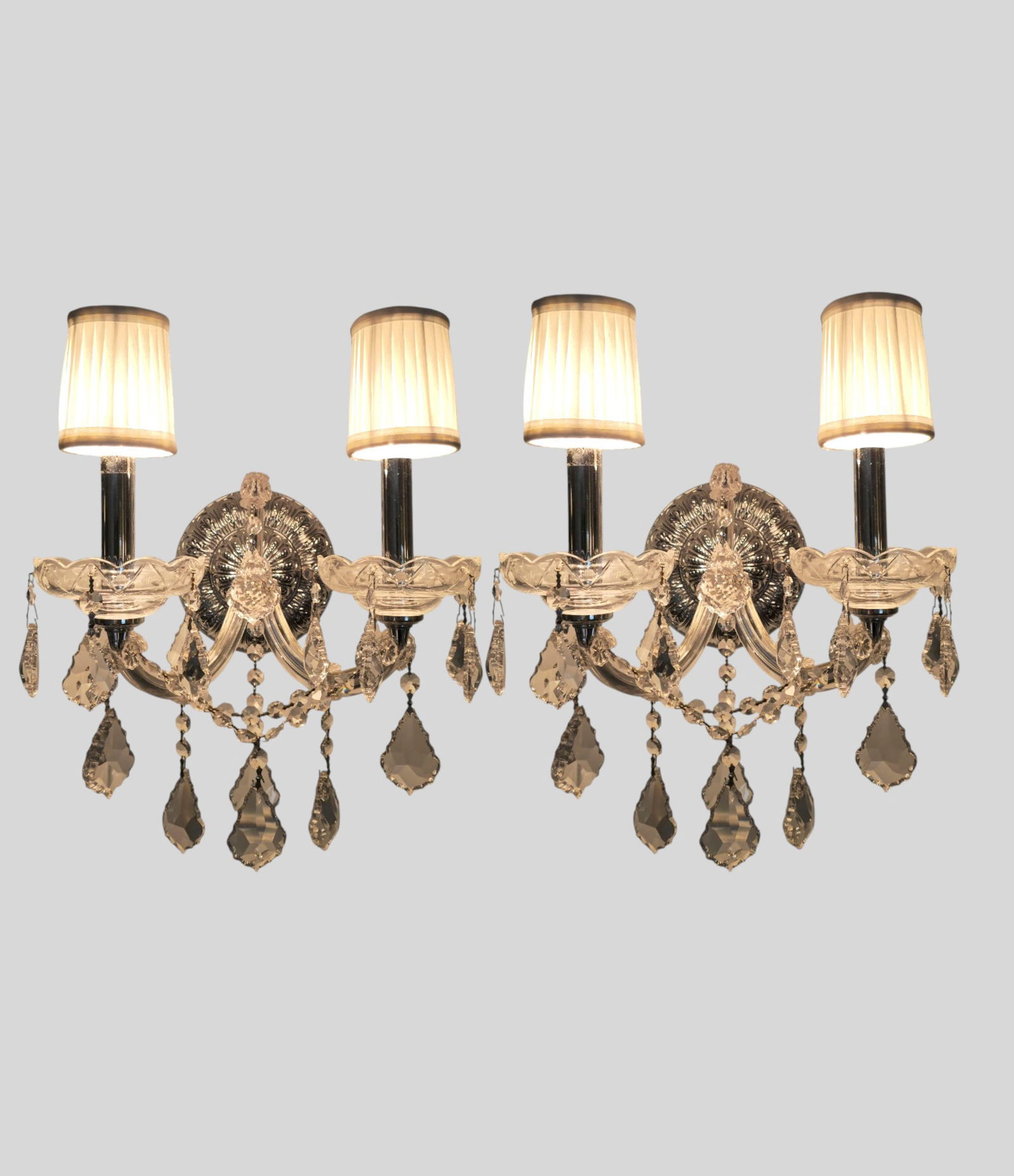 Schönbek Wall Sconces: A pair of Schönbek gilt-metal and crystal wall sconces, late 20th century, fitted with Heritage Hand cut crystal elements. Each two-light sconce with scrolling gilt-metal arms issuing from an