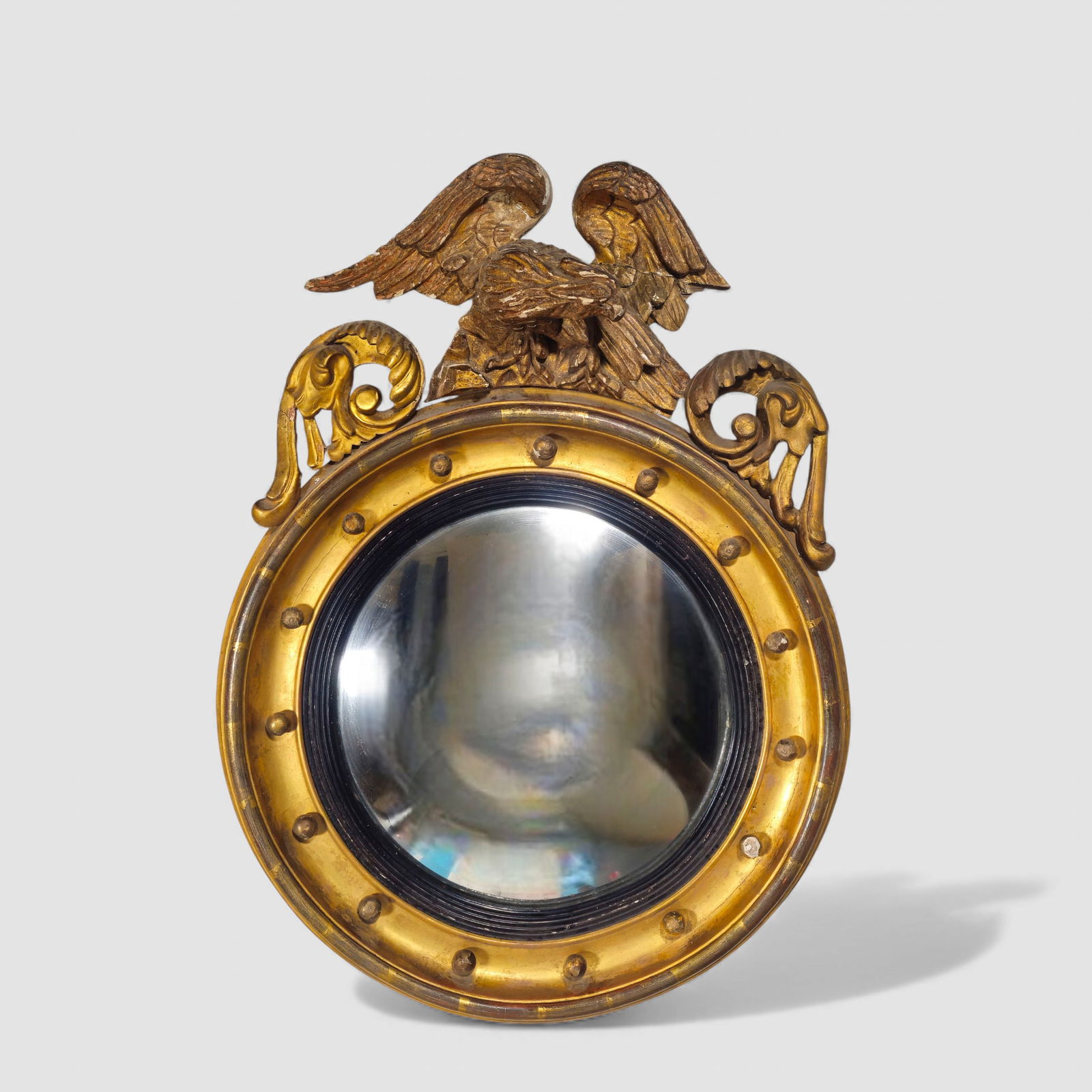 19th Century American Federal Eagle Convex Mirror: 19th Century American Federal Eagle Convex Mirror. Circa 1820. Carved center eagle flanked by scrolled acanthus leaves. Round molded giltwood frame. Ebony interior border. Applied gilt spheres. 23