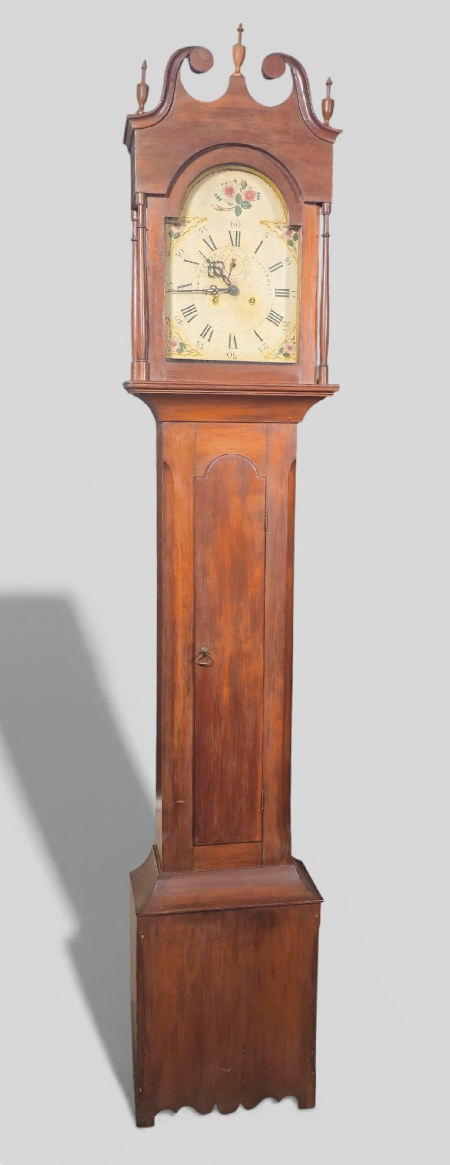 Luman Watson Cherry Tall Case Clock: Luman Watson Cherry Tall Case Clock. Circa 1819-1930. Gilt and polychrome painted face with classical numerals. Wooden works. Cherry case with broken arch bonnet top. Slender body with notched cut cor