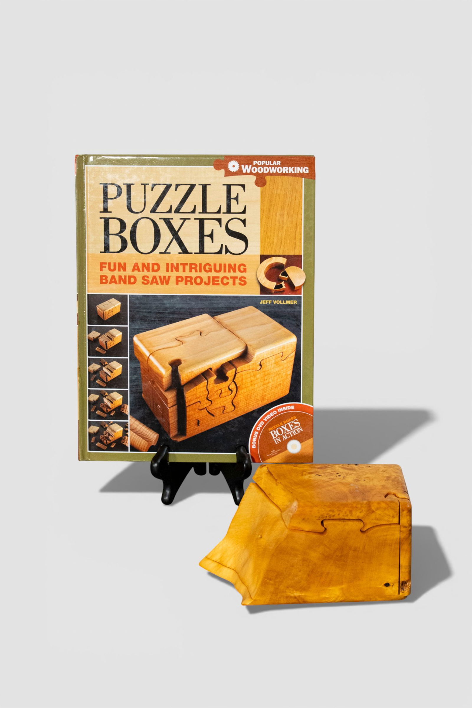 Jeff Vollmer Buckey Burl Puzzle Box: Jeff Vollmer Buckey Burl Puzzle Box. Hand crafted for the Royal Wood Co. Accompanied with an book. Signed to underside. 6 3/4w x 3 1/8d x 3 3/4h.