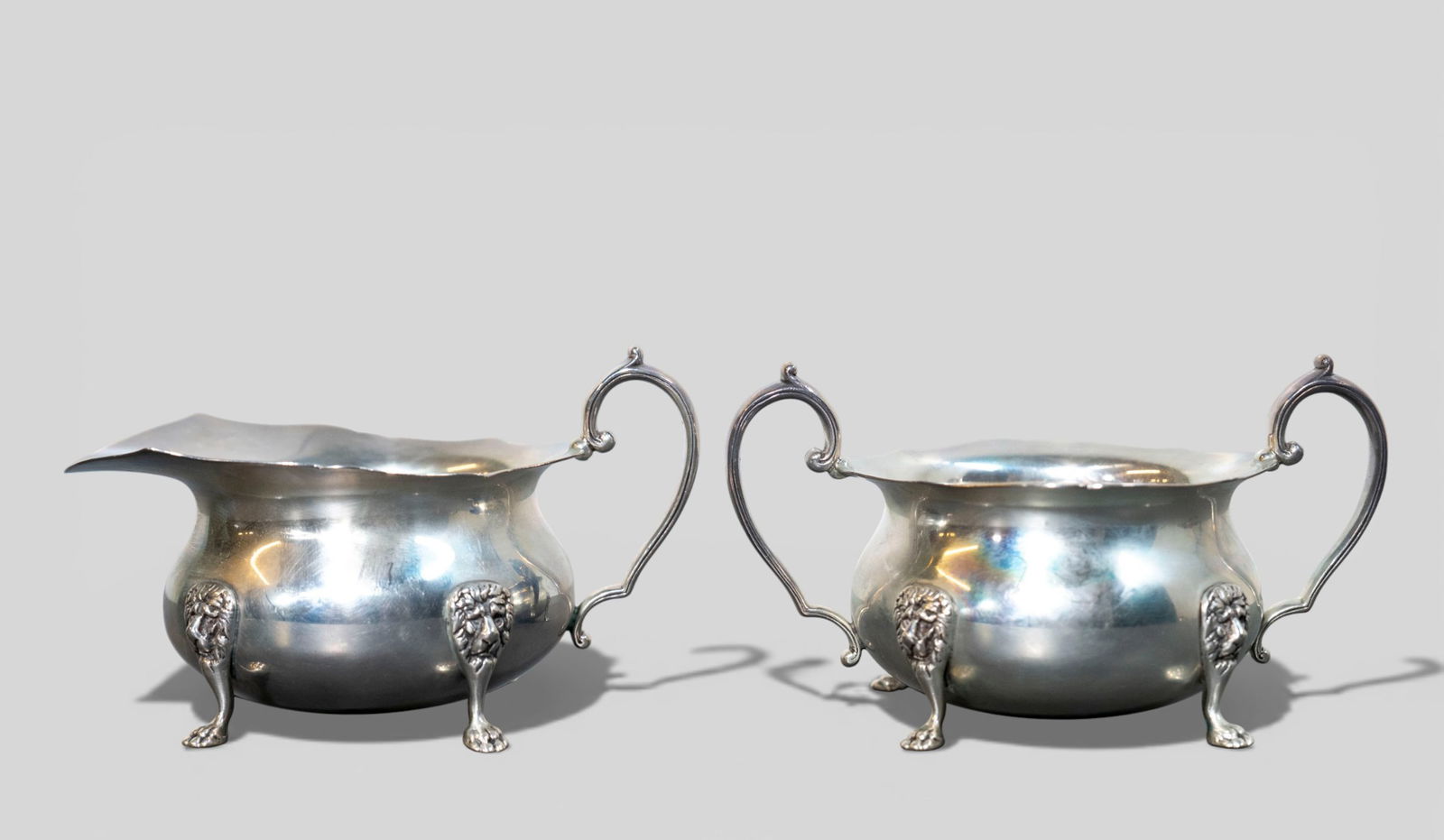 Revere Sterling Silver Lion Head Cream and Sugar, #293: Revere Sterling Silver Lion Head Cream and Sugar, #293 Scalloped rims, scrolled handles and paw feet. Maker's mark to underside, sterling & #293. Creamer - 5 1/4w x 3 5/8d x 3 1/8h. Sugar - 5 3/8w x