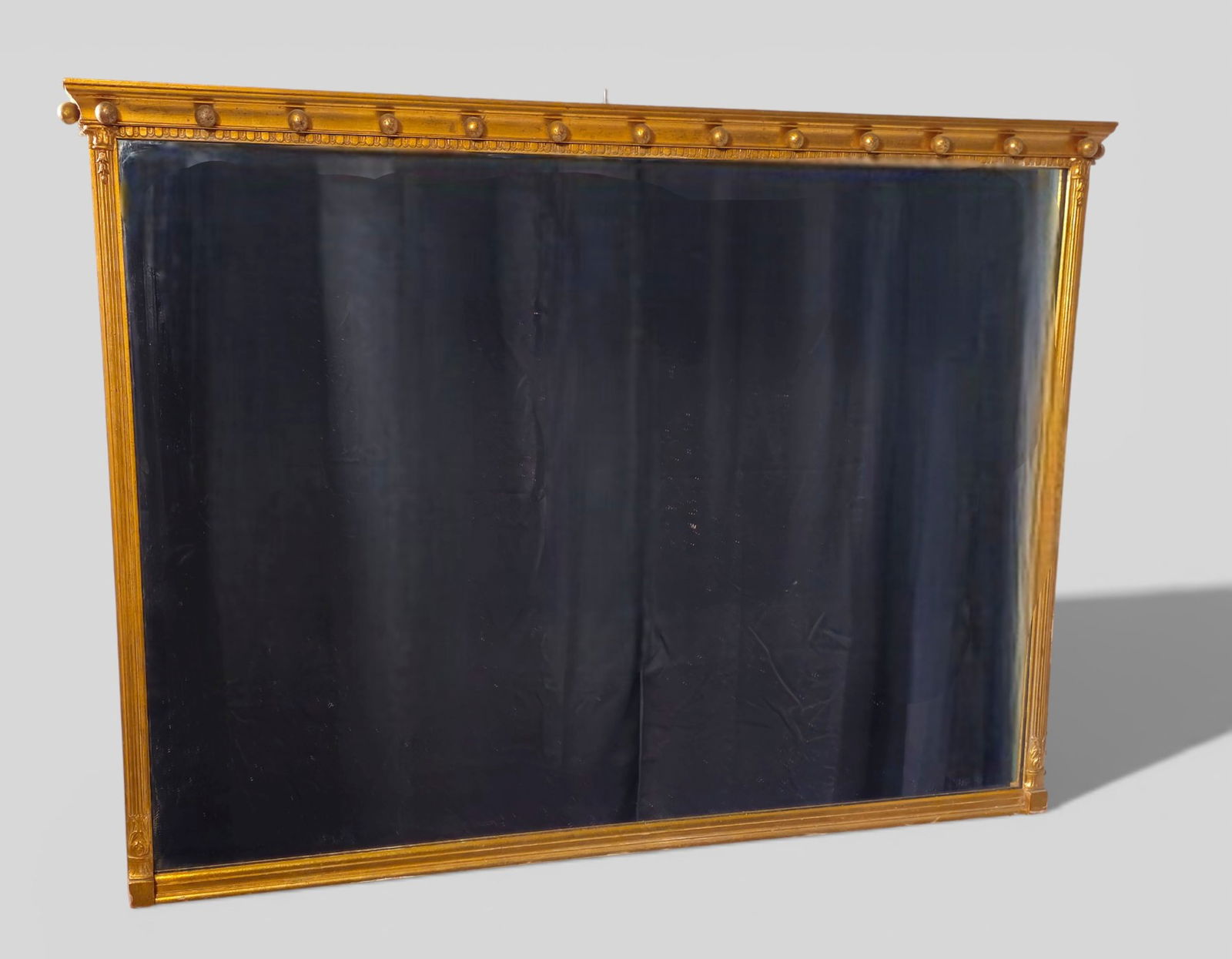 Regency Giltwood Style Rectangular Mirror: Regency Giltwood Style Rectangular Mirror. Circa 1920s. Cove molded top with applied spheres. Fluted sides with quartered bases and capitals. 23 1/2w x 2d x 42 3/4h.