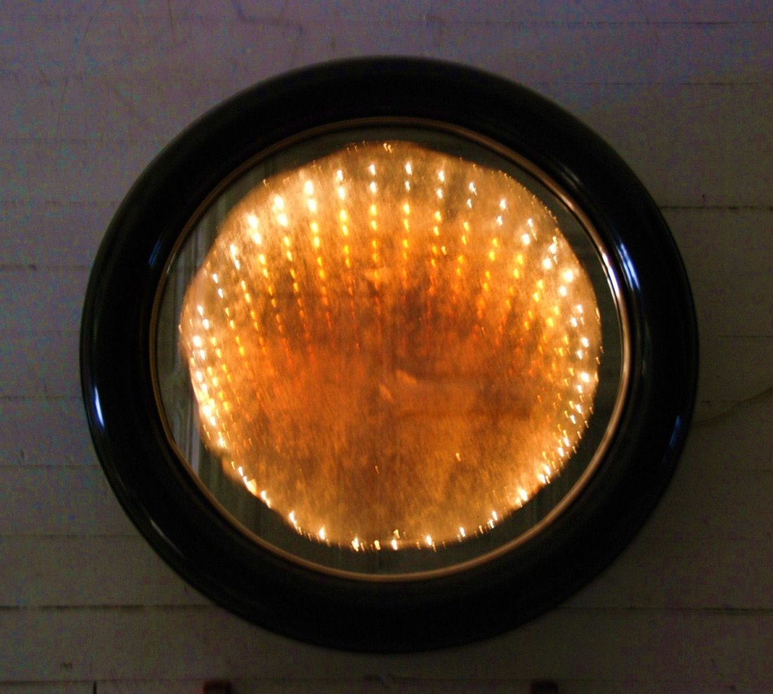 Curtis Jere: Round infinity mirror. Brass trim, plastic, black lacquer, gold wash and mirrored glass. 30.25 x 6.5D