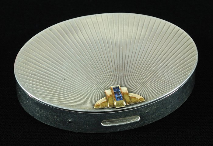 Tiffany Sterling and Gold Compact: Art Deco hinged oval cosmetic box with gold and sapphire clasp. Marked Tiffany & Co. Approx. wgt 2ozt. Approx. 3 x 2.5