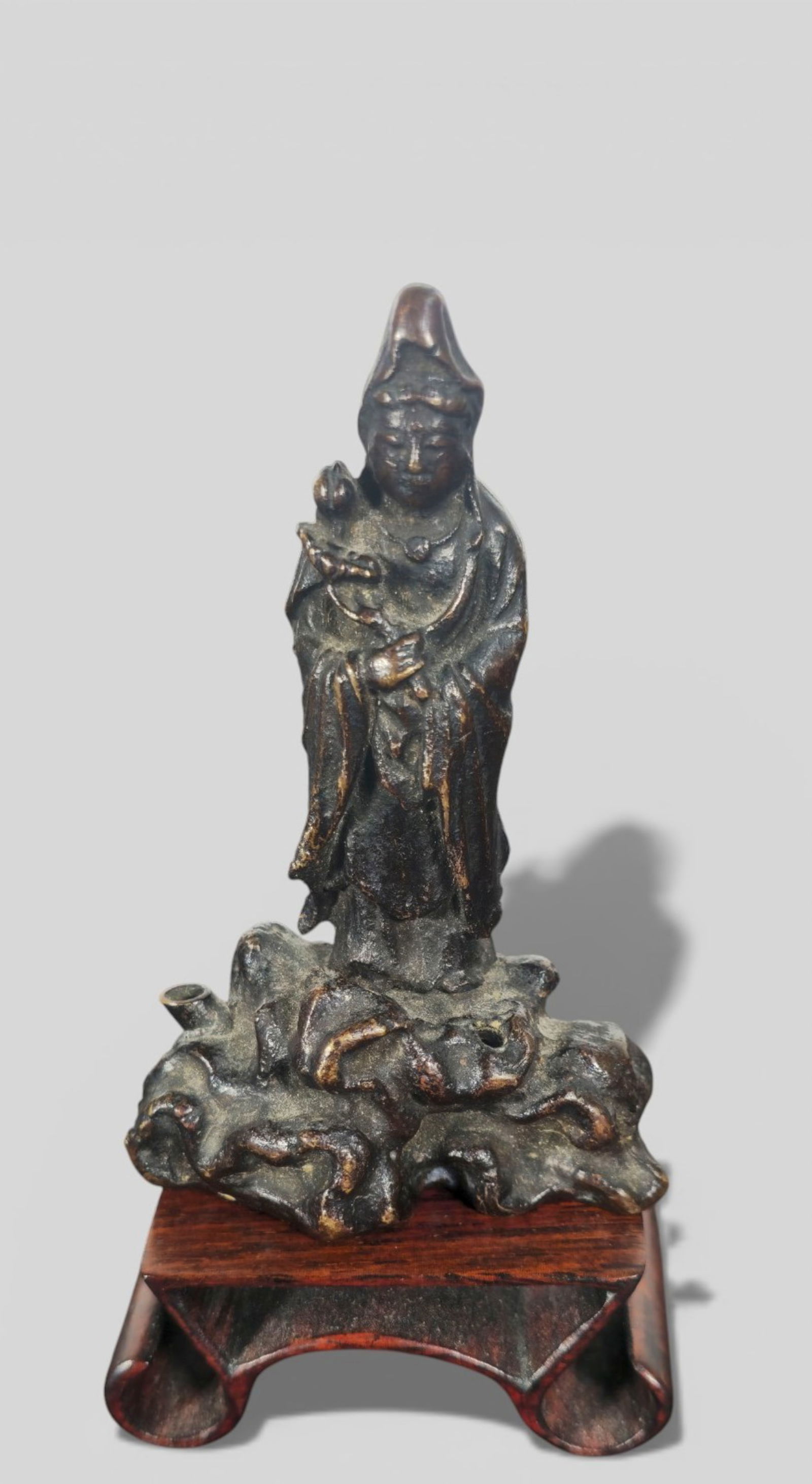 Chinese Bronze Guanyin Water Dropper: Chinese Bronze Guanyin Water Dropper on Rosewood Stand. Chinese bronze Guanyin water dropper presented on a carved rosewood stand, the figure rendered with serene expression and refined detailing. Siz