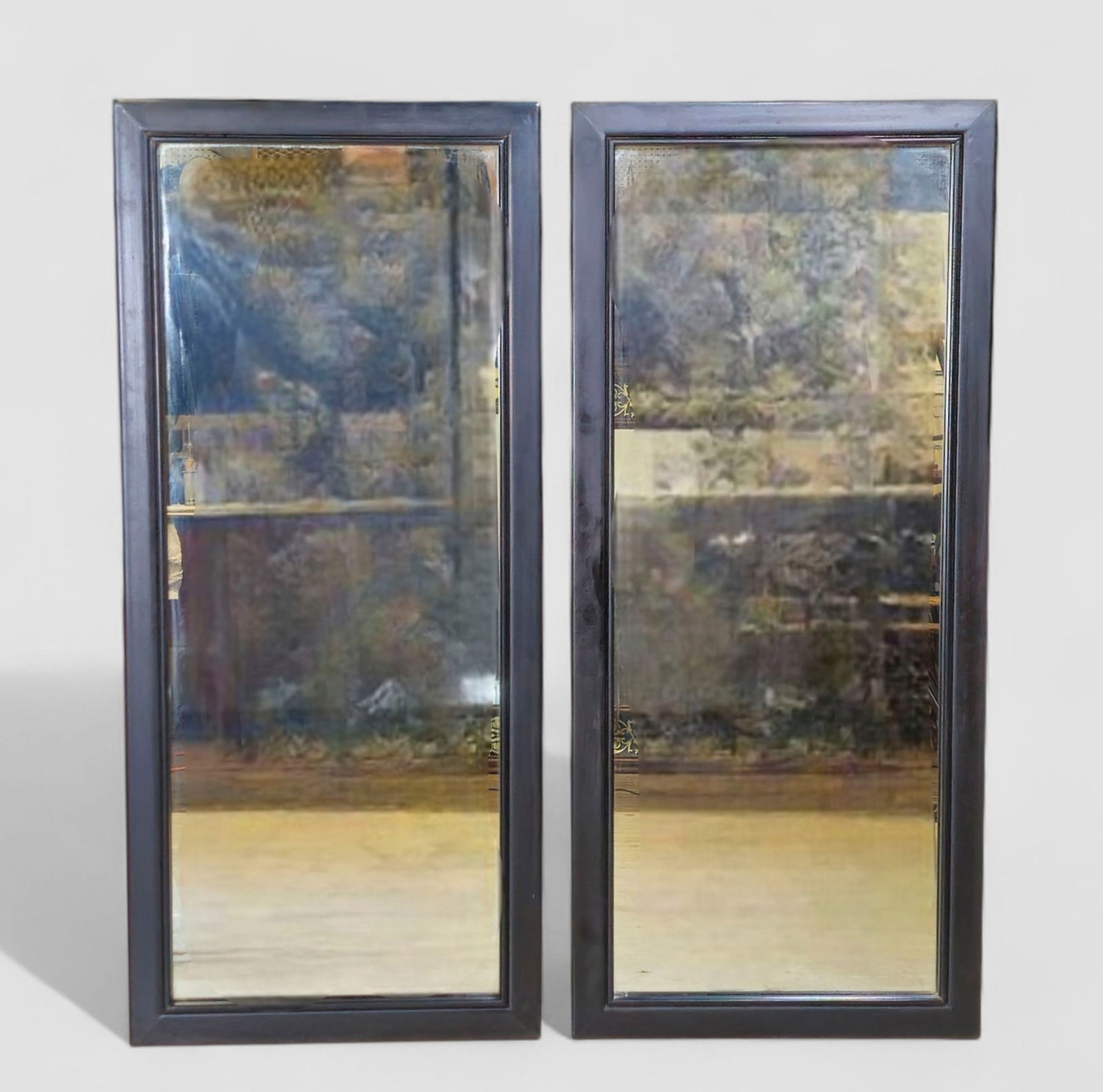 Pair Of MCM Ebony Framed Wall Mirrors: Pair of mid-century modern ebony wall mirrors, each set within a simple stepped black-painted wooden frame. Rectangular in form and versatile in scale, suitable for flanking a console, dressing an