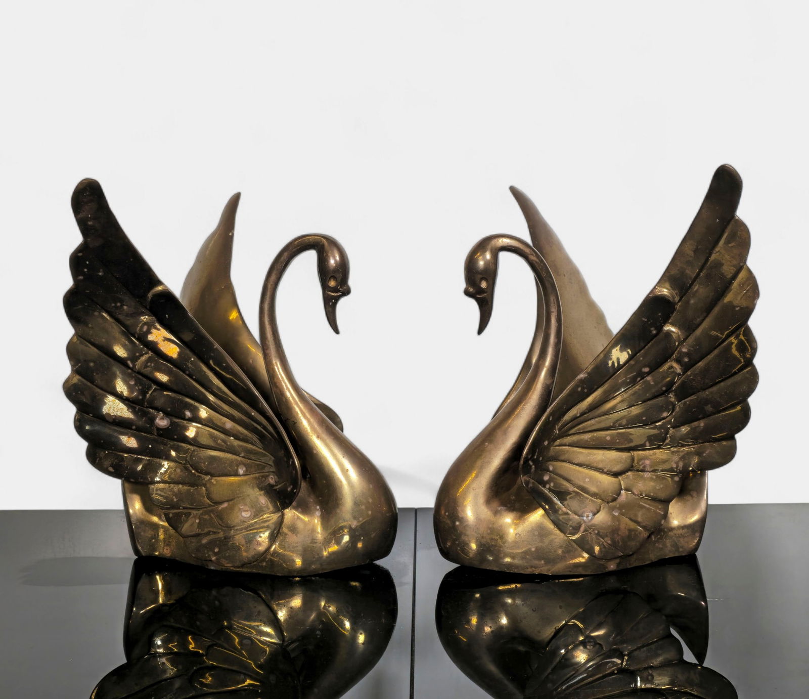 Pair of Vintage Solid Brass Swan Sculptures: A striking pair of vintage solid brass swan sculptures, gracefully rendered with wings raised in a poised and elegant form. The fluid lines and high-quality casting highlight the sculptural detail of