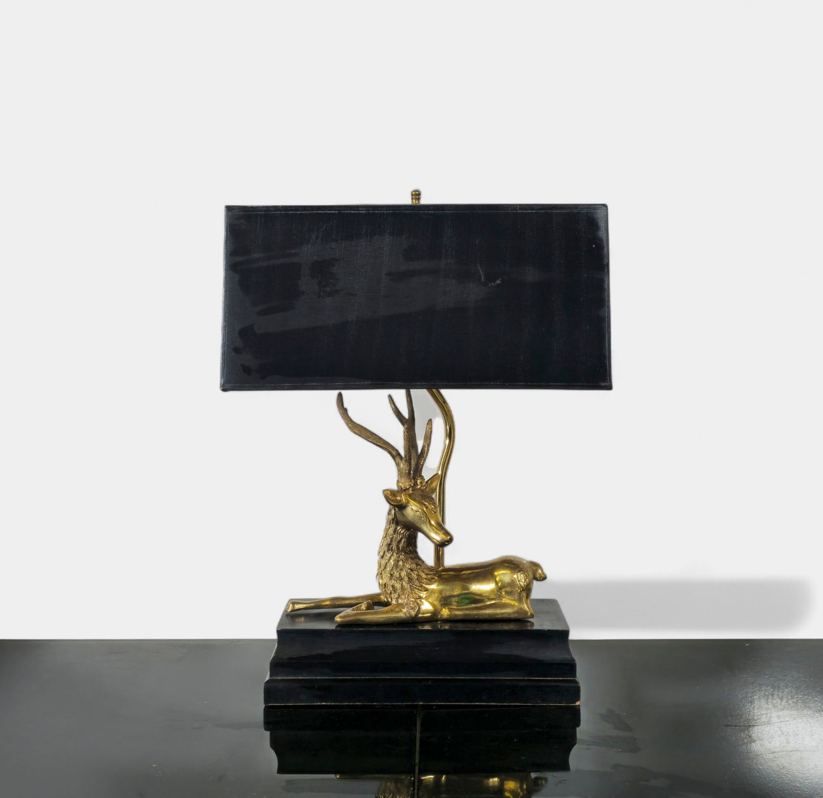 Frederick Cooper Brass Stag Table Lamp: An elegant Frederick Cooper brass table lamp featuring a sculptural reclining stag resting atop a stepped black base. The detailed casting highlights the stag’s textured coat and graceful