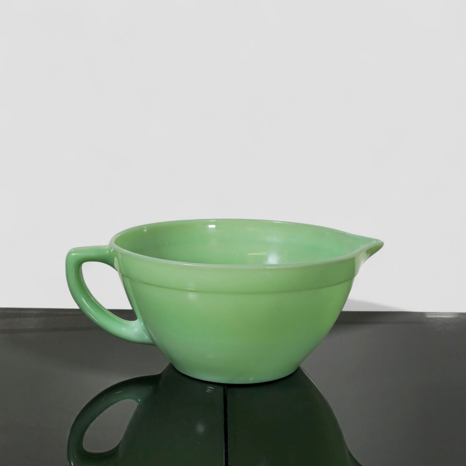 Anchor Hocking Fire-King Jadeite Batter Bowl: Vintage Anchor Hocking Fire-King jadeite batter bowl with single applied handle and molded pouring spout, executed in the classic milky green opaque glass. Underside bears the impressed “OVEN