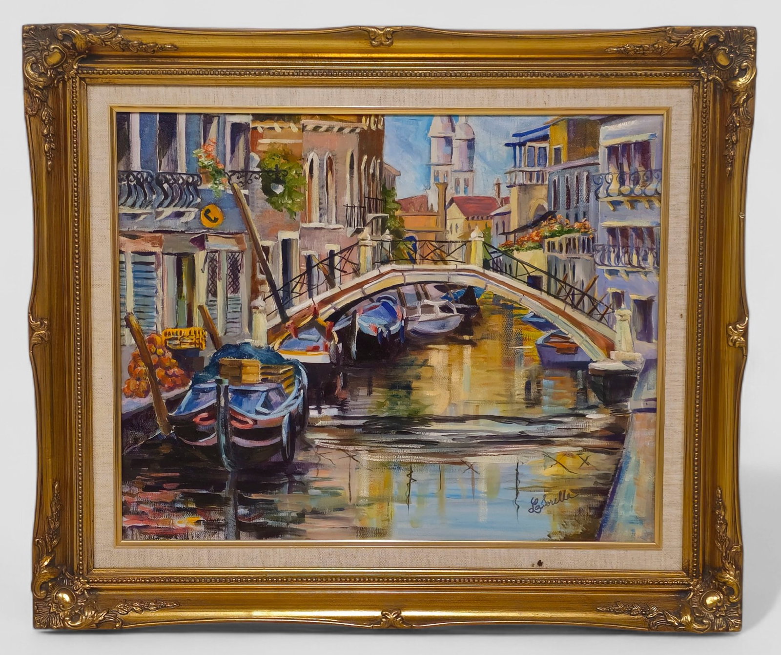 Ursula Lasorella Venice Canal Oil Painting: Ursula Lasorella (American, 20th Century), oil painting depicting a colorful Venetian canal scene with gondolas, arched bridge, and surrounding architecture. Signed lower right. Presented in an