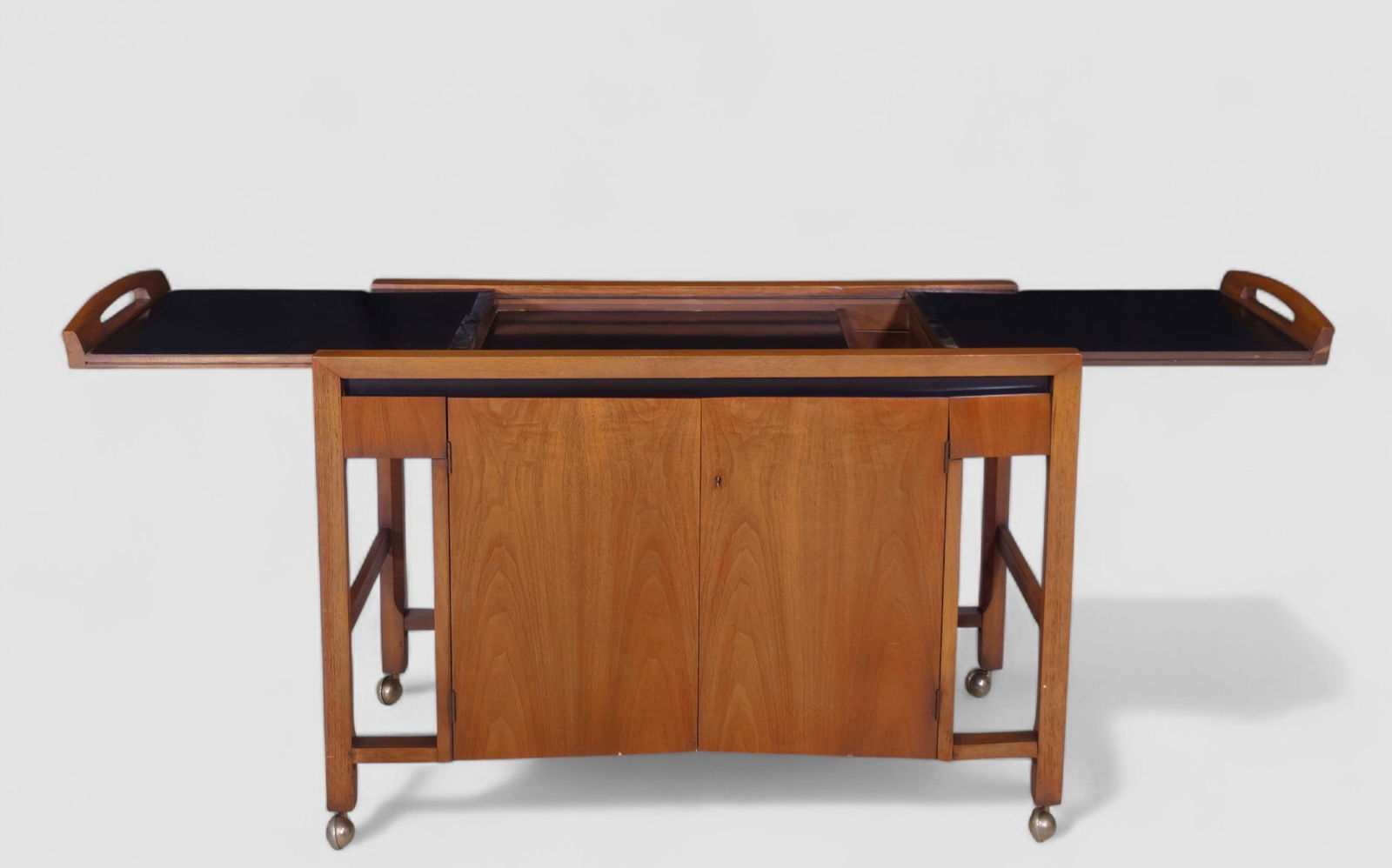 Henry & John Warren Expanding Bar Cart: A mid-century walnut bar cart by Drexel, from the Design for Living line. USA, 1963. stamped “090-530-2 . Design For Living By Drexel” to underside. The cart features dual black