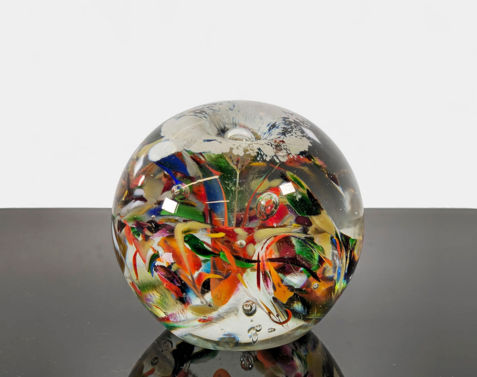 Marty Christy Studio Art Glass Paperweight: A vibrant and dynamic studio art glass paperweight by Marty Christy, featuring a complex internal composition of swirling color ribbons in vivid reds, greens, yellows, blues, and whites, all