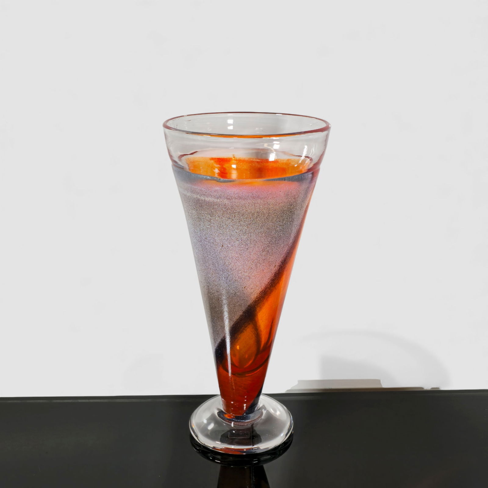 Kjell Engman Kosta Boda Art Glass Vase: Kosta Boda art glass vase by Swedish designer Kjell Engman, featuring a tall conical form with internal swirling orange, red, and charcoal coloration, rising from a clear circular foot. Etched