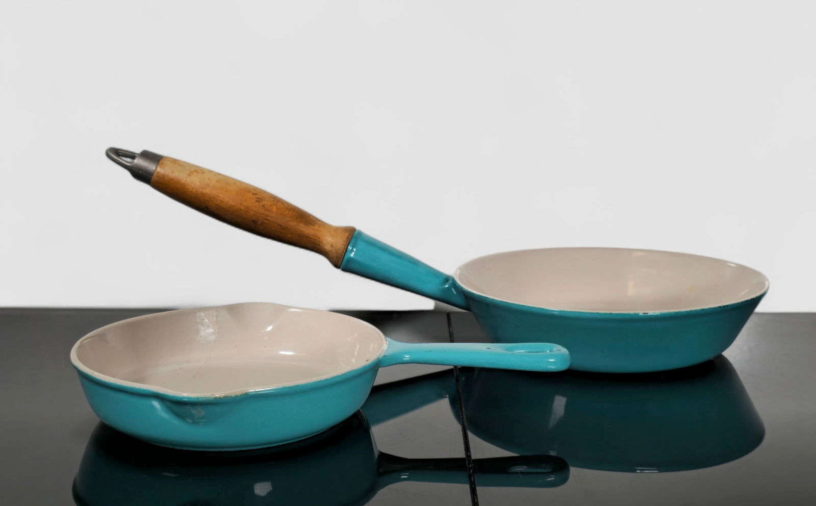 Le Creuset Caribbean Blue Skillets/ Saucepans: Le Creuset Caribbean Blue Skillets/ Saucepans. France. 1970's. Enameled cast iron, walnut and pewter. 18w x 8d x 5 1/4h