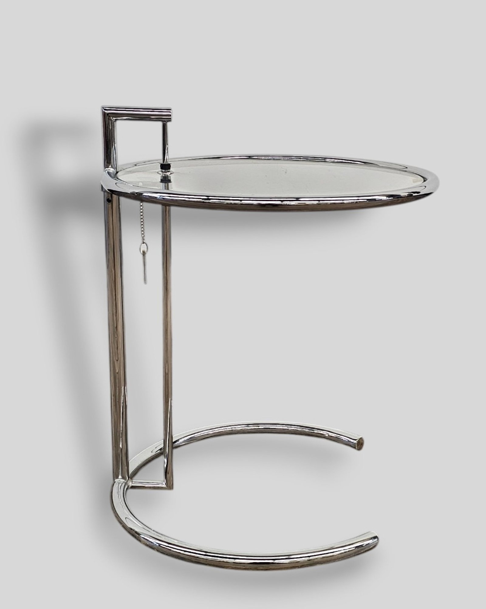 After Eileen Gray E1027 Adjustable Occasional Table: After Eileen Gray E1027 Adjustable Occasional Table. Classicon. 1990s. Chrome tubular steel and glass. 20dia x 25h (Adjustable)