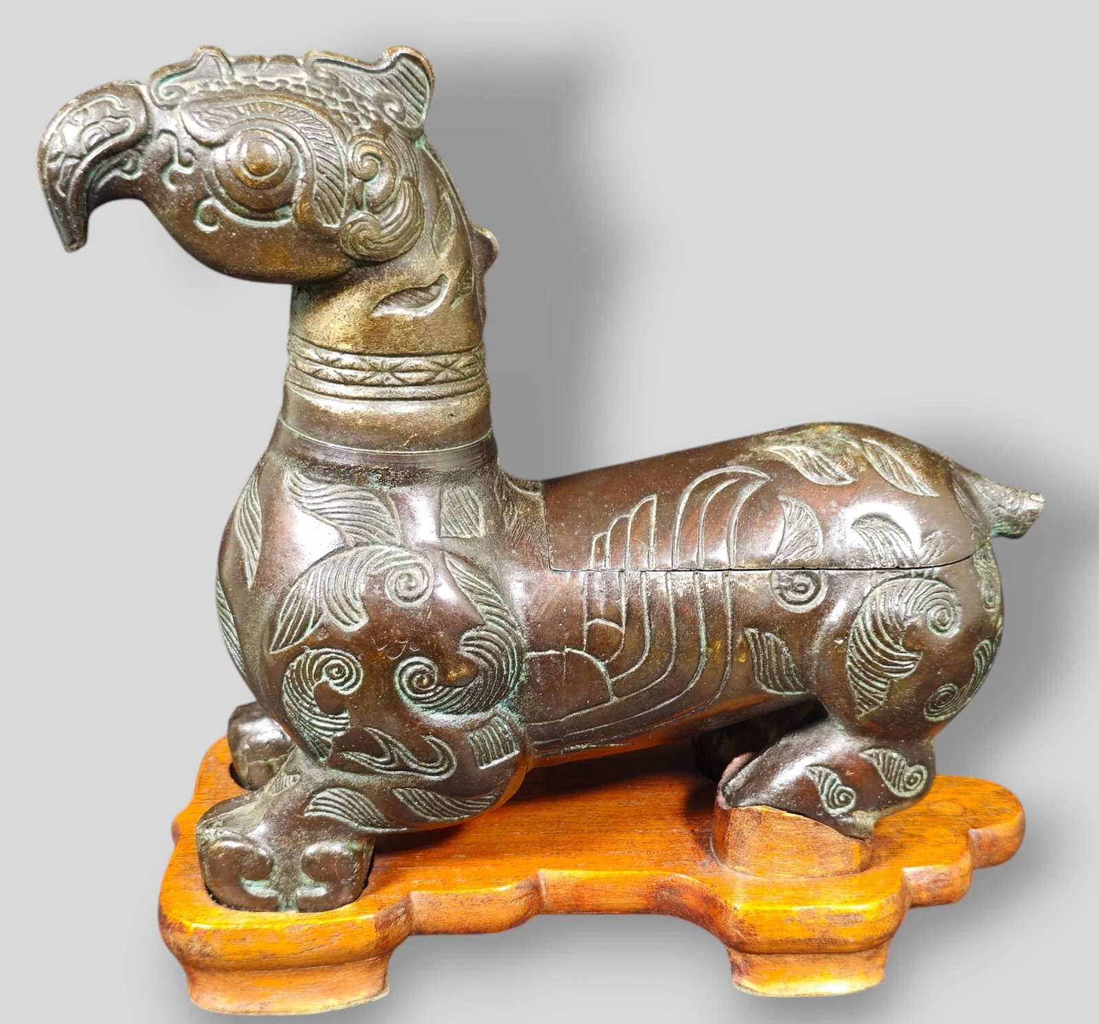 Chinese Bronze Griffin Cigarette Box and Lighter: Chinese Bronze Griffin Cigarette Box and Lighter. 20th Century. Griffin rest on fitted teak base. Head removes concealing a lighter. The tail is the handle with a hinged lid concealing a hidden