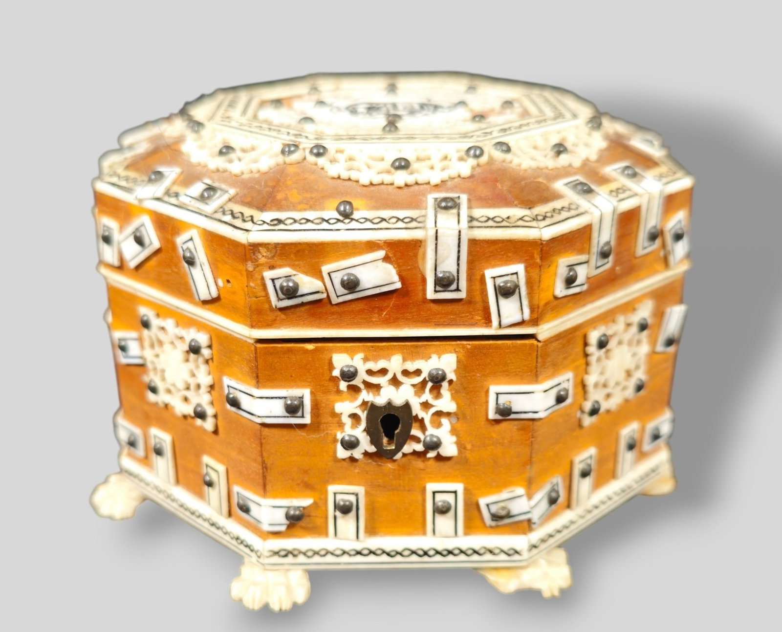 Indian Sandalwood Inlay Mounted Table Box: Indian Sandalwood Inlay Mounted Table Box. Octagonal form with hinged lid. Ebony inlaid elephant to top. Great inlaid borders. Box rests on hairy paw feet. 4 1/2w x 4 1/2d x 3h.