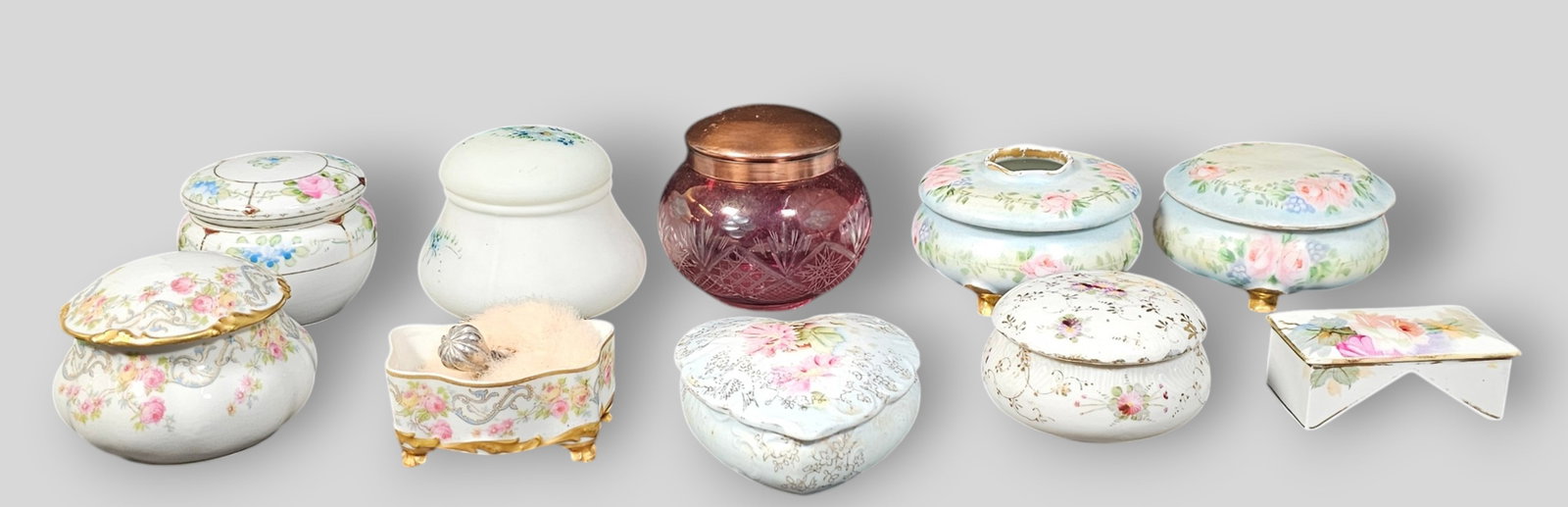Assembled Porcelain Powder Jars or Dresser Boxes: Assembled Porcelain Powder Jars or Dresser Boxes. 6 porcelain, Cranberry cut glass, Satin glass, odd porcelain bow and open top powder box on legs. Manufacturer's names Limoges, Nippon, Prussia, & Roy