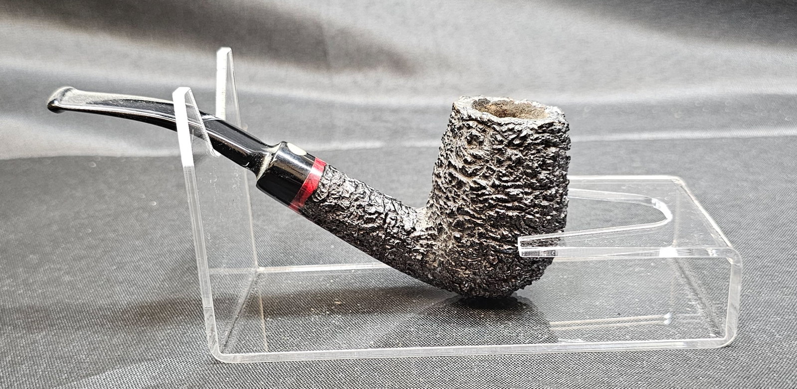 Brugo Pesaro Mastro de Paja Pipe: Brugo Pesaro Mastro de Paja Pipe. Italian briar tobacco pipe with deeply rusticated dark finish, contrasting red-stained smooth maker's panel, bent black mouthpiece, red accent at shank and