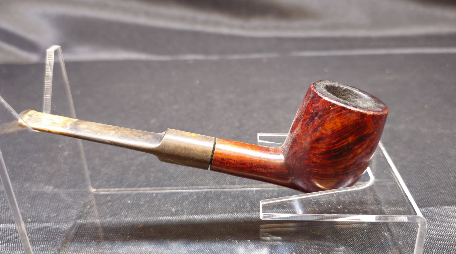 Charatan’s Make London Briar Pipe: Charatan’s Make London briar tobacco pipe, Made in England, featuring a polished reddish-brown finish with pronounced grain and a straight saddle stem. Shank additionally bears patent number