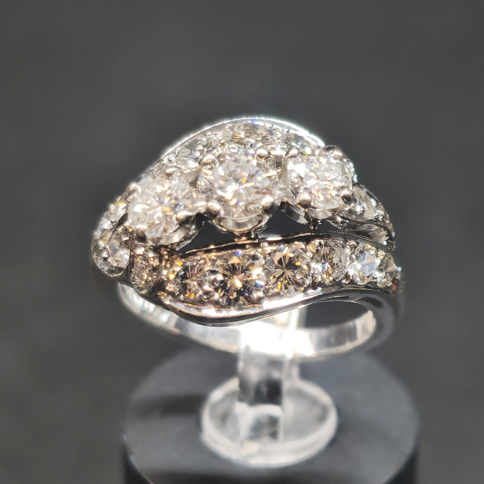 Art Deco Platinum & Diamond Ring: Art Deco platinum and diamond ring, circa 1920s-1930s, featuring a central round-cut diamond surrounded by graduated round-cut diamonds in an elaborate asymmetrical bypass-style setting, accented thro