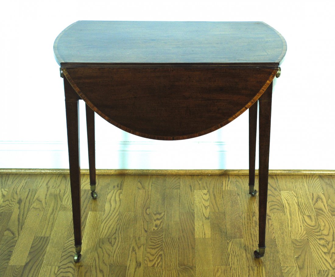 Inlaid Hepplewhite Pembroke Table: Mahogany with satinwood cross banding and string inlay, oval top with drop leaves, one drawer with oval brass pulls and false drawer on other end, tapered legs with string inlay and original brass cas