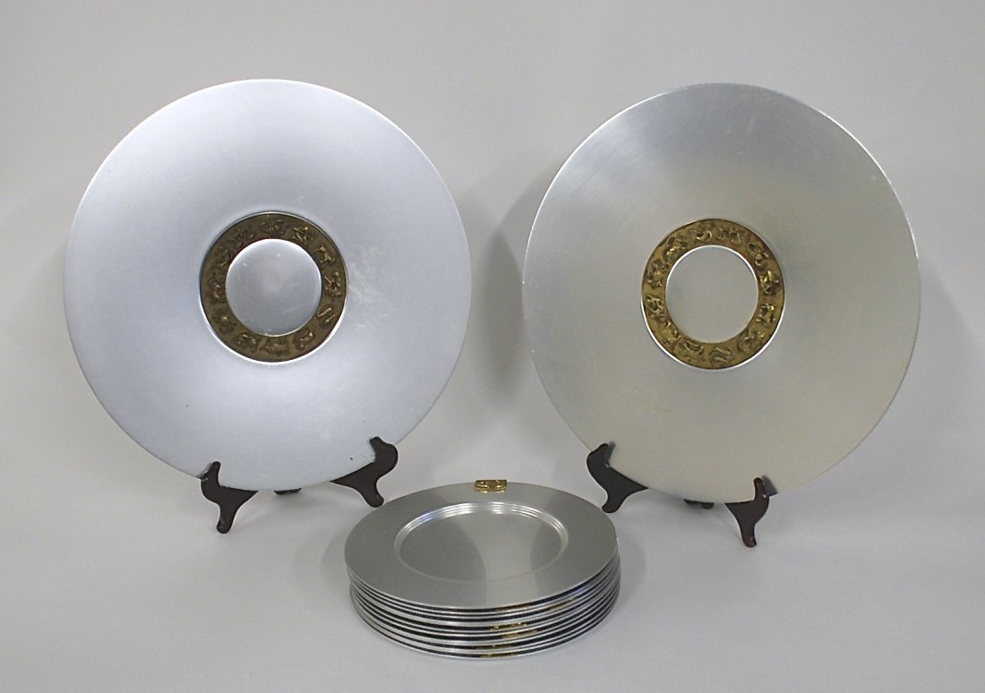 Lurelle Guild: Set of twelve dinner plates and two chargers with brass Zodiac symbols. Aluminum and brass. Size Chargers 18 dia.