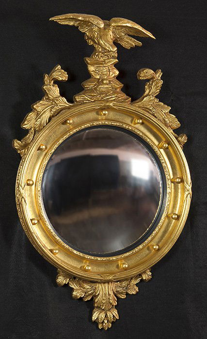 Federal Style Eagle Mirror: Circular bullseye mirror surmounted by an eagle and two carved foliate crests over the convex plate set in conforming frame. Size 43h x 25w.