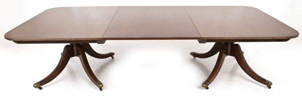 Early 20th Century Mahogany Dining Table(Early Baker): Double pedestal base, Duncan Phyfe legs, cut out corners, brass caps. One large leaf, (37.5w) Size 56w x 117l x 28.5h .