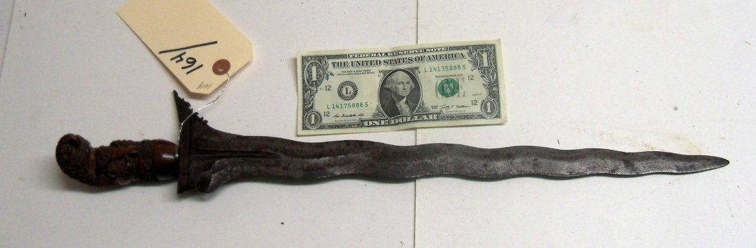 Very fine19th Century Malaysian Kris Dagger Sword: The handle is a well carved raksha a grotesque human figure or demon. The blade is 15½ inches long. Nicely grained and shaped wooden scabbard. This kris is from The William Herbert McGinty Collection
