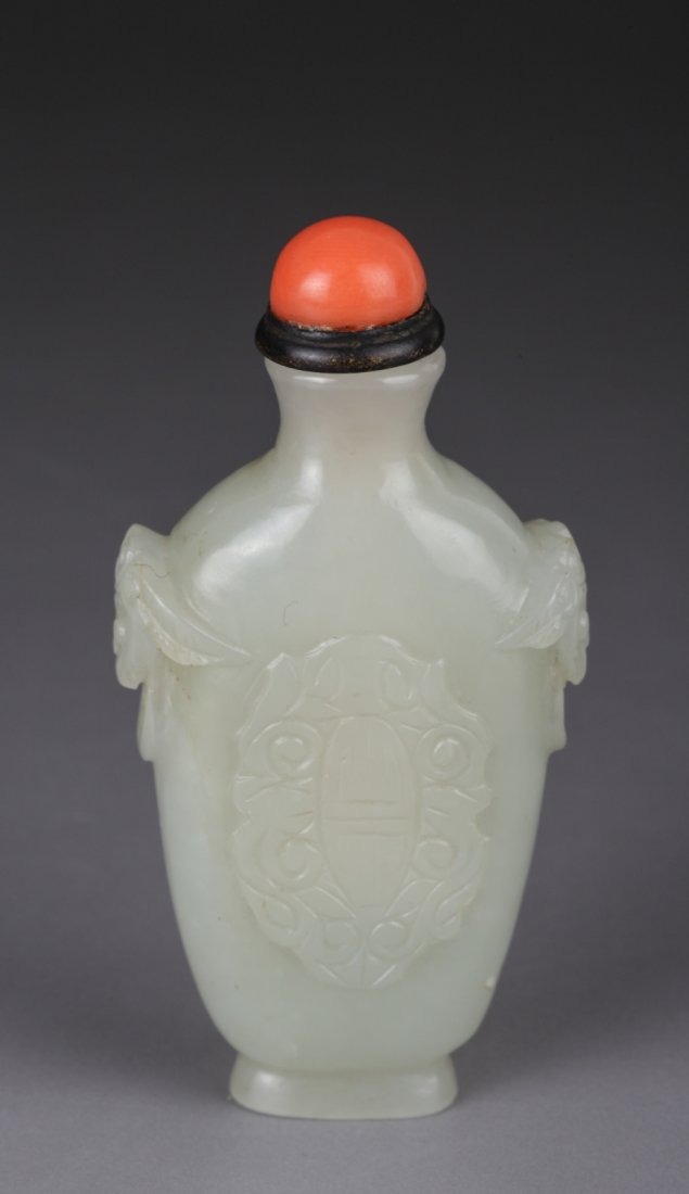 Chinese Vase-shaped White Jade Snuff Bottle: Vase-shaped white jade snuff bottle carved front and back with a "shou" character; the sides with well carved Buddhist-lion heads holding fixed rings; Chinese coral half-bead stopper. Dimension: 2 3/4
