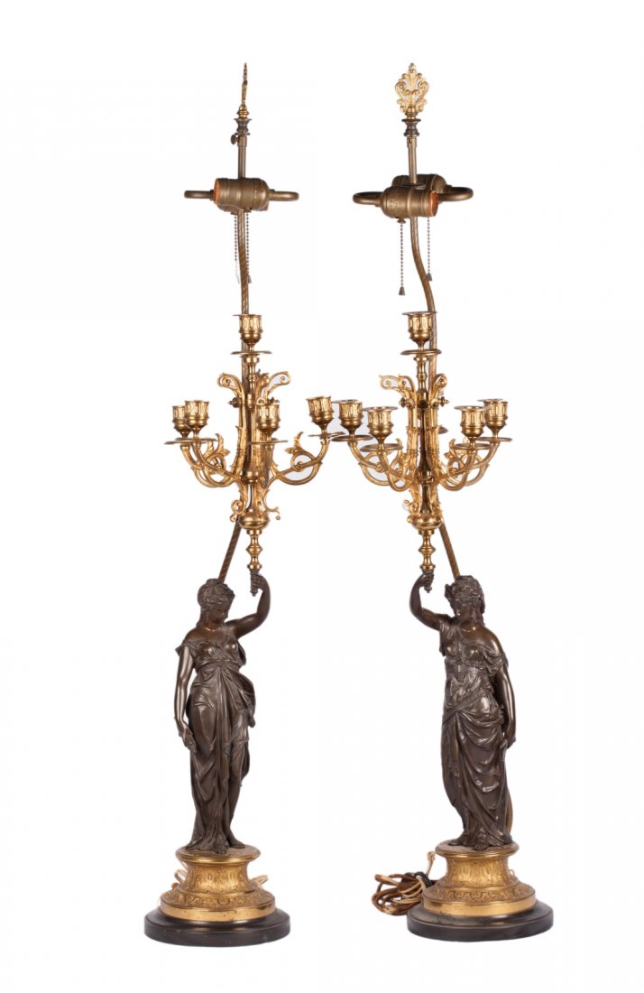 Pair of Dark Patina Bronze Female Statues: Pair of Dark Patina Bronze Female Statues on Gilded Bronze and Black Marble Base. Figures holding gilded bronze candelabra light fixtures. Shades included. Dimension: 41"H