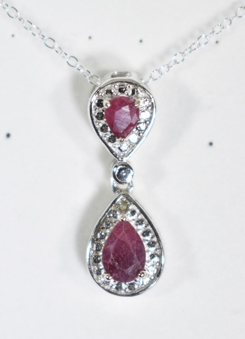 PEAR CUT RUBY DANGLE DROP NECKLACE: IN STERLING SILVER. CONTAINS 1-4X6mm AND 2-3X4mm PEAR CUT RUBY GEMSTONES WITH BEAUTIFUL RUBY RED COLOR. METAL IS FASHIONED TO REFLECT LIGHT IN A HALO AROUND GEMSTONES. DROP MEASURES 3/4" LONG. SET IN 