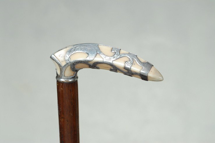 A very nice Art Deco silver over ivory cane: A very nice Art Deco silver over ivory cane. The hippo ivory "L" handle is 1 1/3" high and 4 1/2" long. It is carved to a point on each end and the top, bottom, and sides are carved with hard-angled e