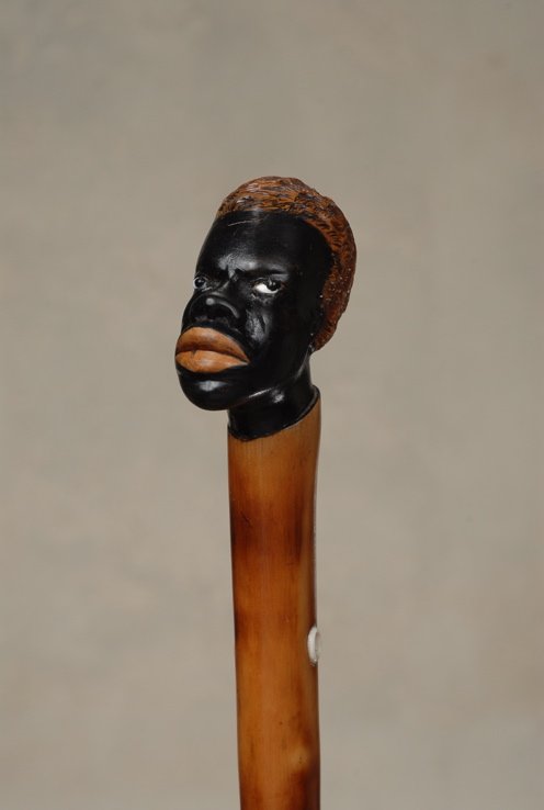 A very nice wood black man cane: A very nice wood black man cane. The hardwood handle is 2" high and 2" at its widest. It depicts a very detailed black man with brown hair, white glass eyes, black painted skin and thick red lips. The