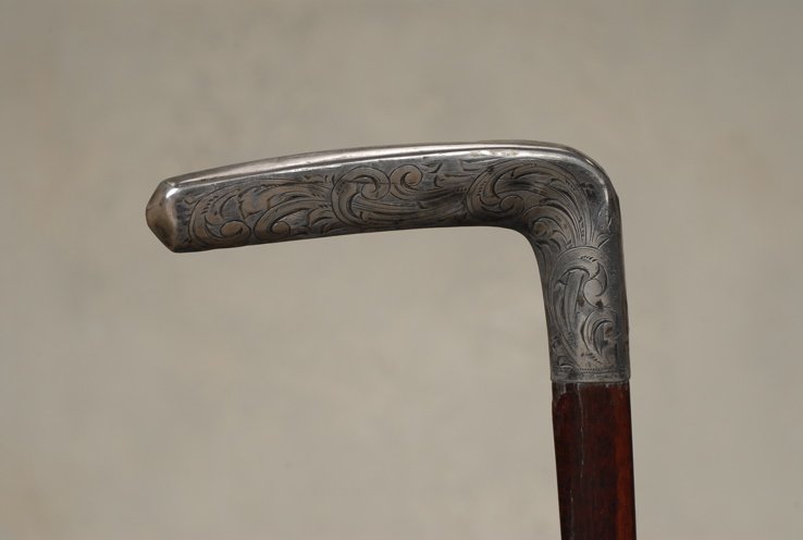 A very nice silver and snakewood Art Deco cane: A very nice silver and snakewood Art Deco cane. The entire stick is configured in a triangular shape, and the silver "L" handle is 2" high and 3 1/2" to the side. It is elaborately decorated in "C" sc