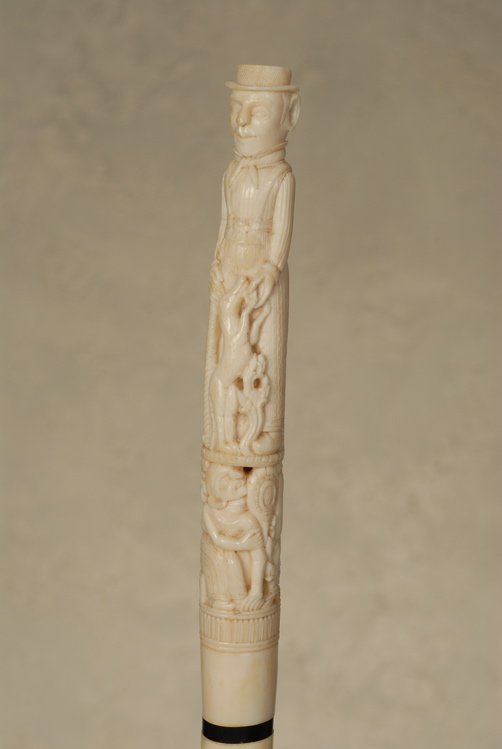A nautical cane of a man on twist-carved whalebone: A very nice ivory nautical cane of a man on twist-carved whalebone. The marine ivory handle, probably walrus, is 7 1/2” long and 1” at its widest. It depicts a full-bodied man with his jumping dog