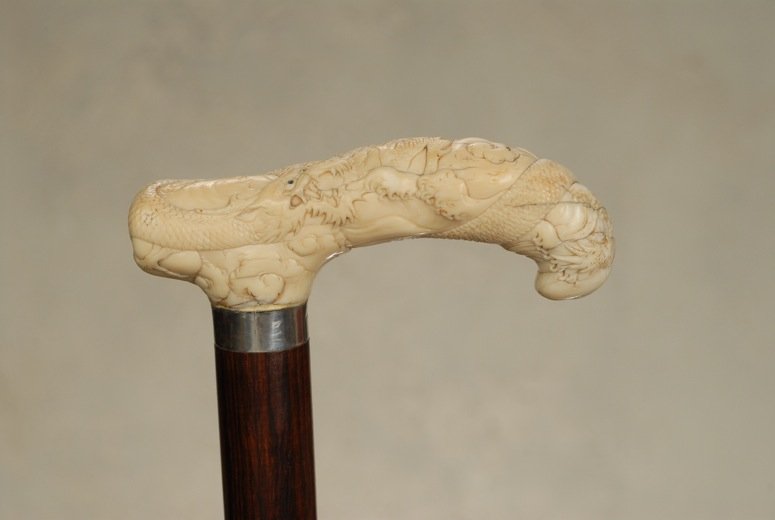 A very nice ivory Japanese dragon cane: A very nice ivory Japanese dragon cane. The ivory tau handle is 1 1/2” high and 4 1/3” long. It depicts a wrapped, three-toed Japanese dragon with abalone eyes, floating amongst stylized clouds. T