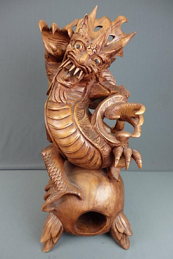 Wooden Carved Bali Dragon: From the Novica Collection Indonesia. Carved in the wood on the bottom Subrata Bali. No damage on it. Single carved piece with a loose rolling ball in the bottom. Stands 20 inches in height, 8 inches 
