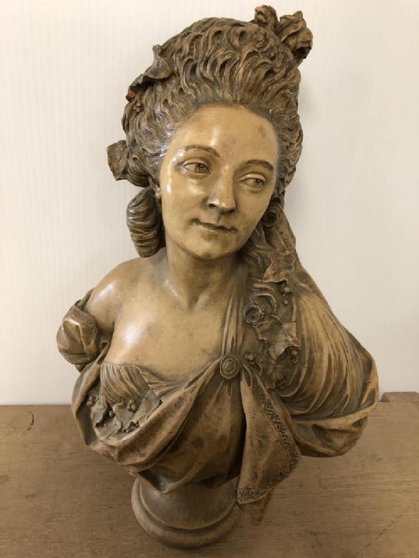Plaster bust of a woman: Female with curls and flowers in her hair looking away, garment off one shoulder. Some chips in curls and thin crack on face. About 28 inches tall, 17 inches wide and 10 inches deep. No apparent signa