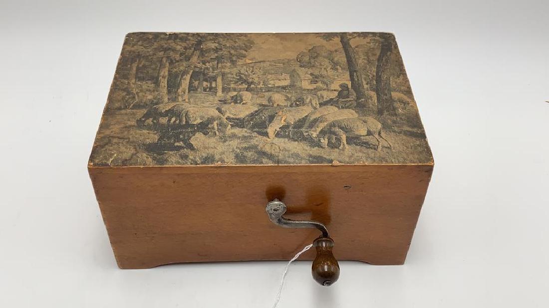 Table top antique crank handle music box: Wood case with paper decorated lid- Young girl attending her sheep, crank handle, plays for tunes, Swiss works, sweet note inscribed on bottom To Dolly from Mamma and Daddy 1926, 4 1/2 inches tall by 
