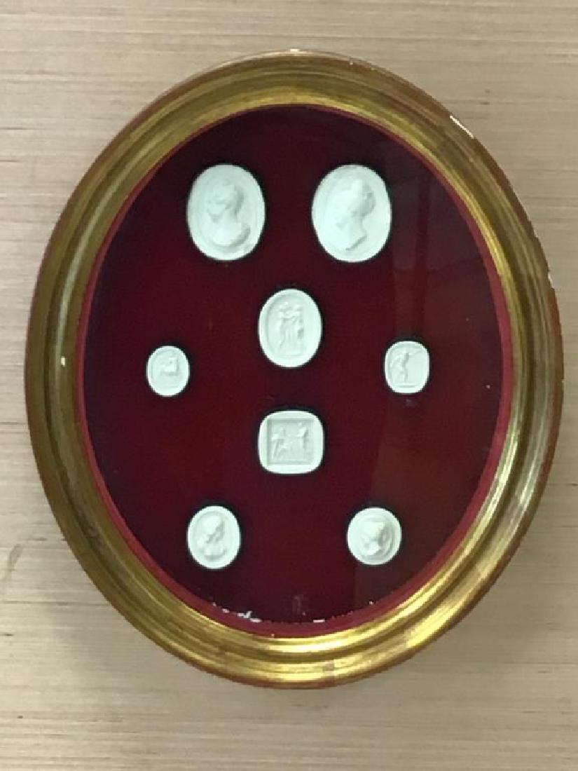 Framed Cameo Shaped Gesso Medallions: Eight Framed Cameo Shaped Gesso Medallions mounted on red velvet set in oval gilt shadow box frame. Chips on gold paint of frame and flakes of medallions have fallen inside box, see photos. Frame meas