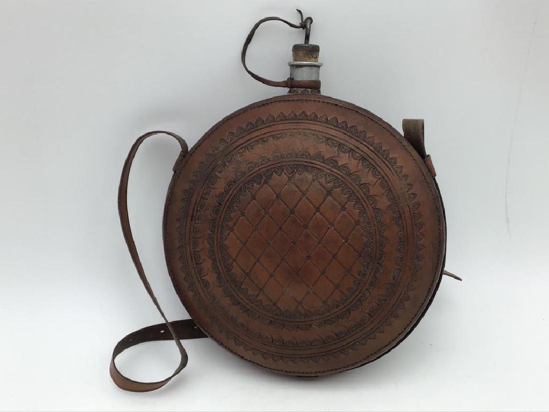 Mario Hanel Leather Coveted Canteen: No stopper. Side is marked Mario Hanel Stayton ore 97. Canteen itself is aluminum. 8 inches wide. Provenance: from the Estate of Raymond Bentley