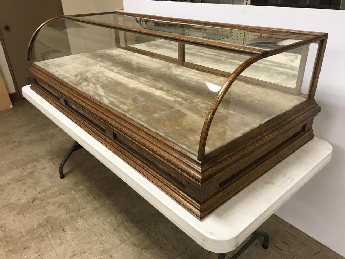 Oak store display case: Vintage oak Store display has curved front, two sliding rear drawers, and to hinge doors that fold down. Needs some repair to the front left – see photo. No key 18 x 61 x 28 inches.