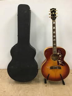 Gibson Guitar J-200 & Case: Lot includes a Gibson J-200 "Standard Jumbo Guitar" plus stand and case. Gibson has sunburst design on front, maker label inside, inlay design and Gibson name, has 6 strings, wood in nice condition. B