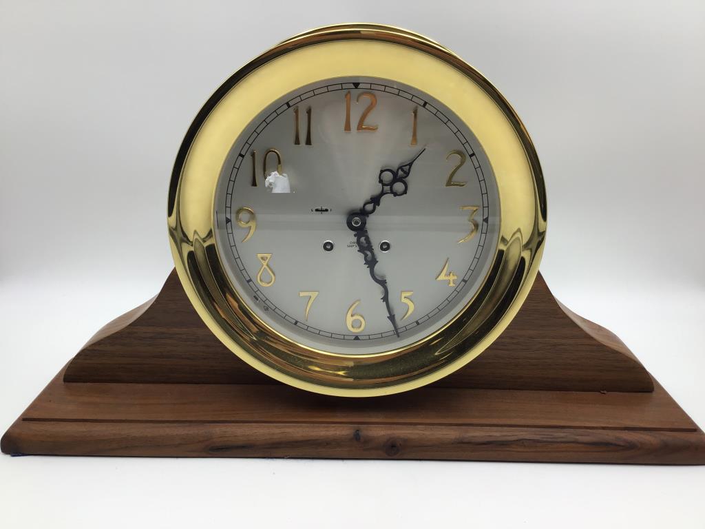 Chelsea Ship's Bell Clock: brass frame clock on wood mantel stand, face reads Chelsea Ship's Bell, overall nice condition, not tested. Measures approximately 12 inches high by 20 1/2 inches wide by 5 inches deep. From the Raymo