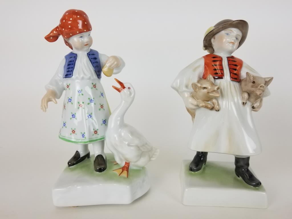 2 Herend figurines: Girl feeding a goose and Boy with piglets figures. Both measure approx 7 1/2 inches tall.