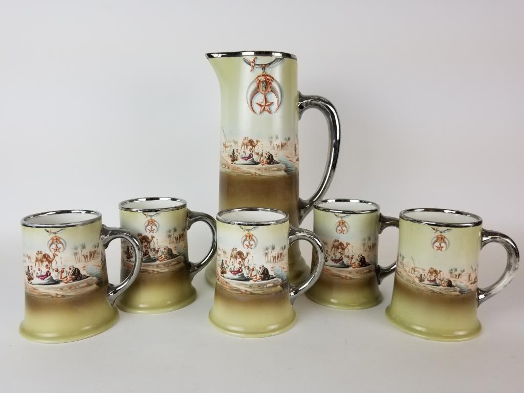 Shriner's Masons pitcher and 5 mugs: Pitcher and 5 matching mugs. Shriner's symbol and desert scene. W.H. Tatler Decorating Co. Pitcher measures 12 inches tall. Some wear to the silver handles and rims.