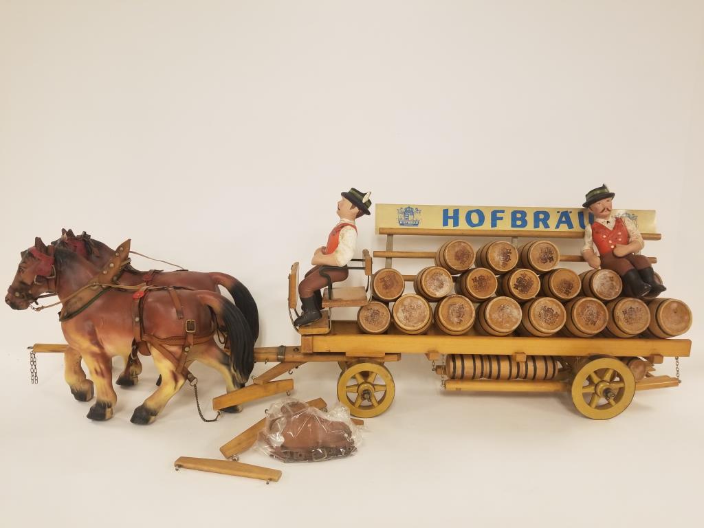 Vintage 40 inch long Hofbrau Bavaria beer barrel wagon: 4 plastic horses with a wooden barrel wagon. Advertising for Hofbrau Bavaria, sign on wagon is tin. Comes with 2 different sized barrels. Driver and rider arms are jointed. Marked Leika. Wagon measure
