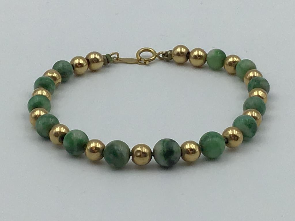 14 Karat yellow gold and jade bracelet: graduated green jade beads separated by 14 karat yellow gold beads, marked 14 K, 6.75 inches long